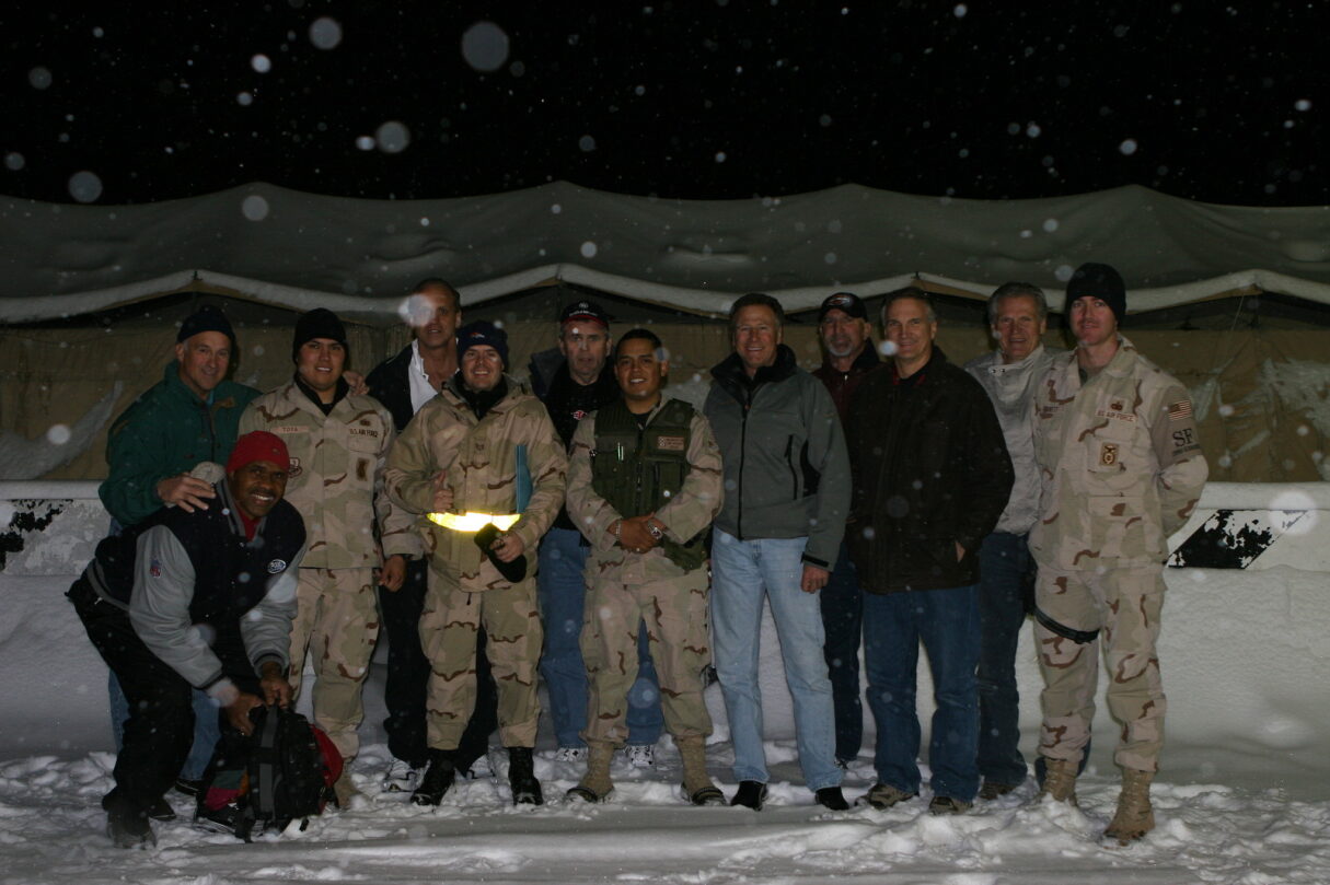 Randy Gradishar with military personal in the snow in front of a military tent 